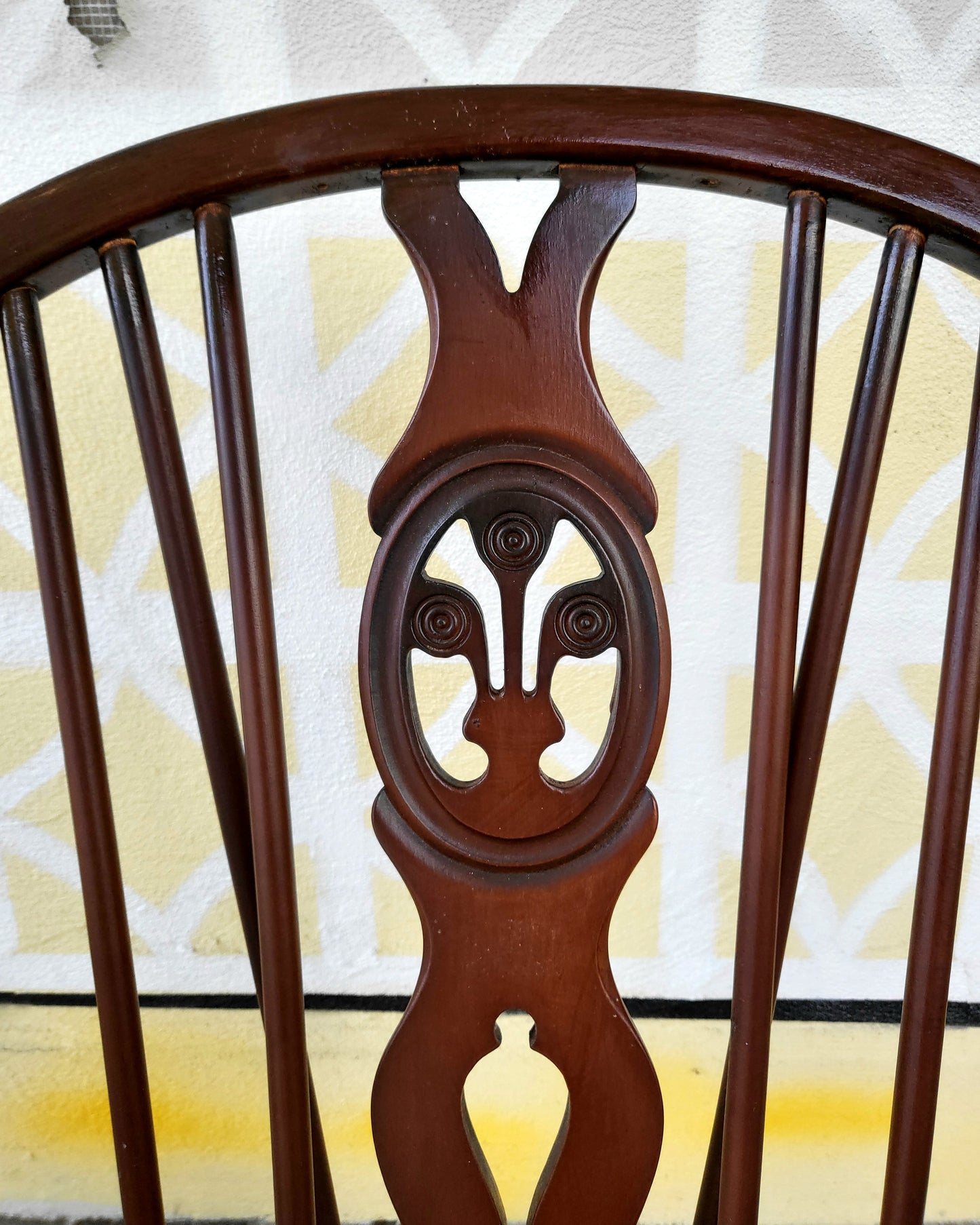 Detail of Ercol Prince of Wales chair showing elegant spindle backrest and carved central back support in beech wood.