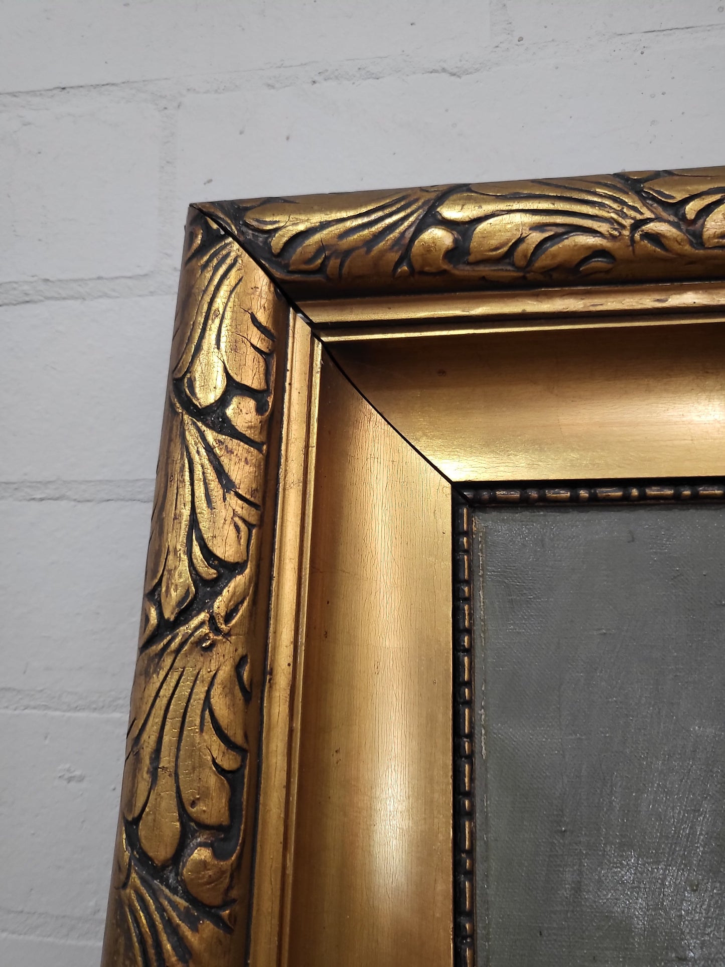 Ornate gold gilt frame with stepped design and decorative carvings, antique oil painting circa 1920s.