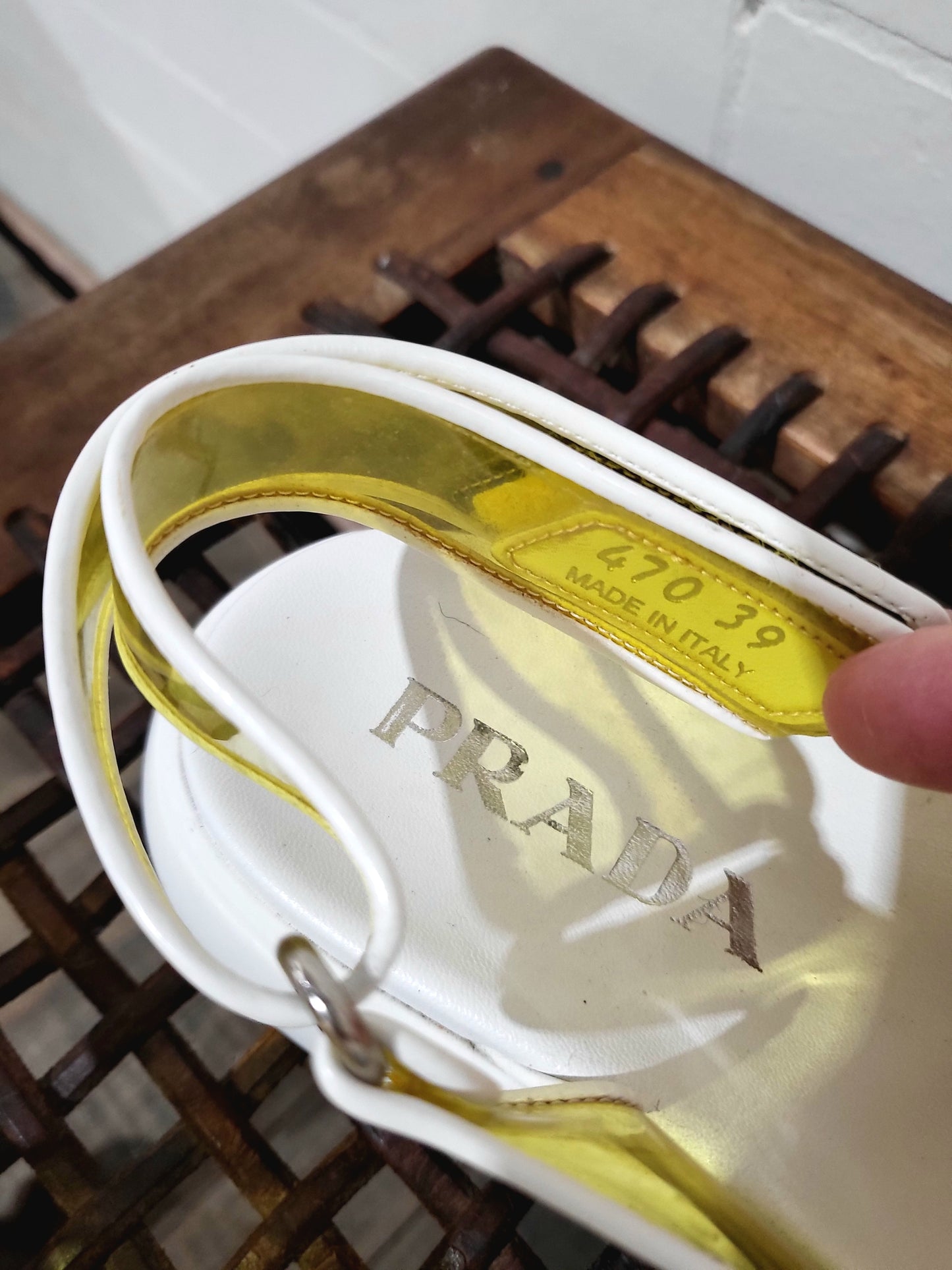 Close-up of Prada logo tab and velcro fastening on transparent yellow sandals.