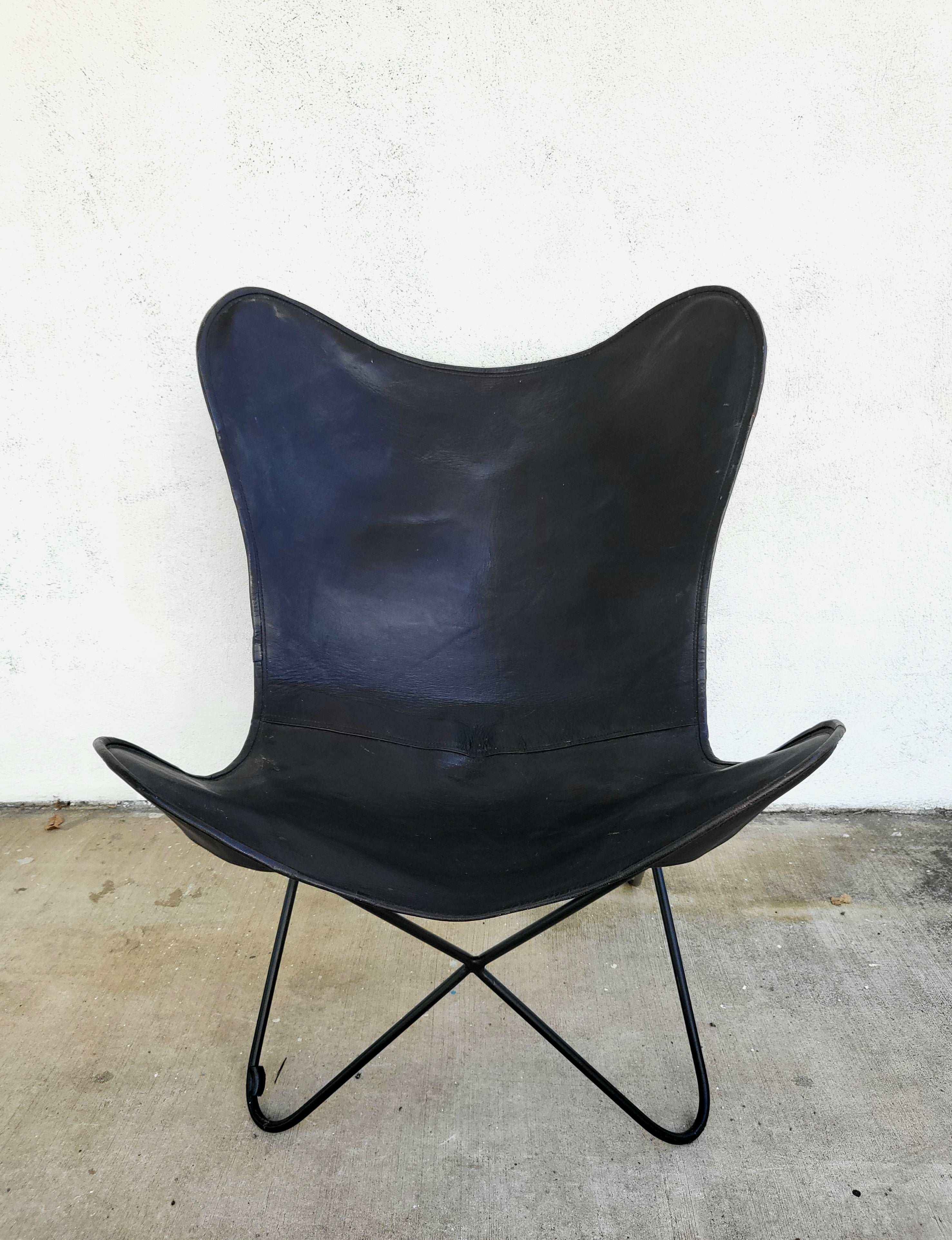 Black leather butterfly chair with sculptural metal frame, photographed against a white background.