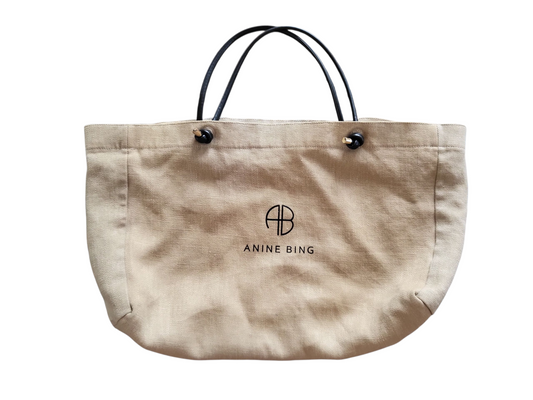 Anine Bing linen and cotton tote bag in natural beige with black handles and AB monogram, available at Saint Atlas