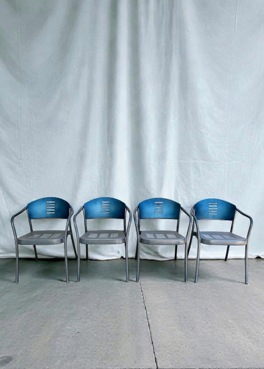 Four Vico Magistretti chairs lined up against a white curtain backdrop