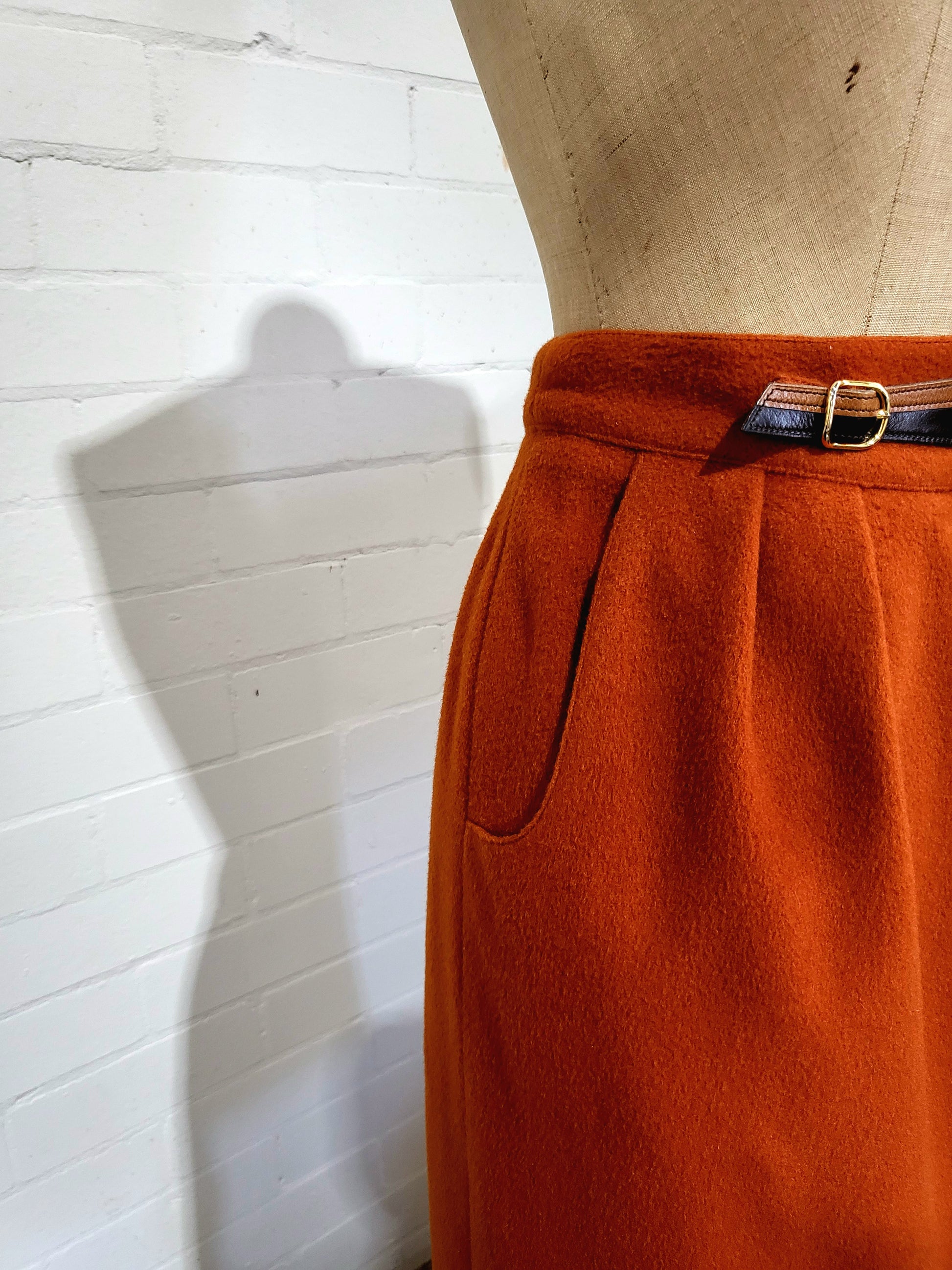 Side view of Hermès 1980s high-waisted rust skirt showing pocket and pleats