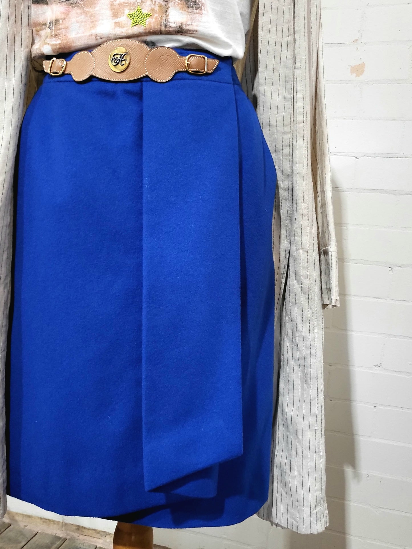 Detail of camel leather waistband with gold-tone Hermès H button on vintage cobalt skirt