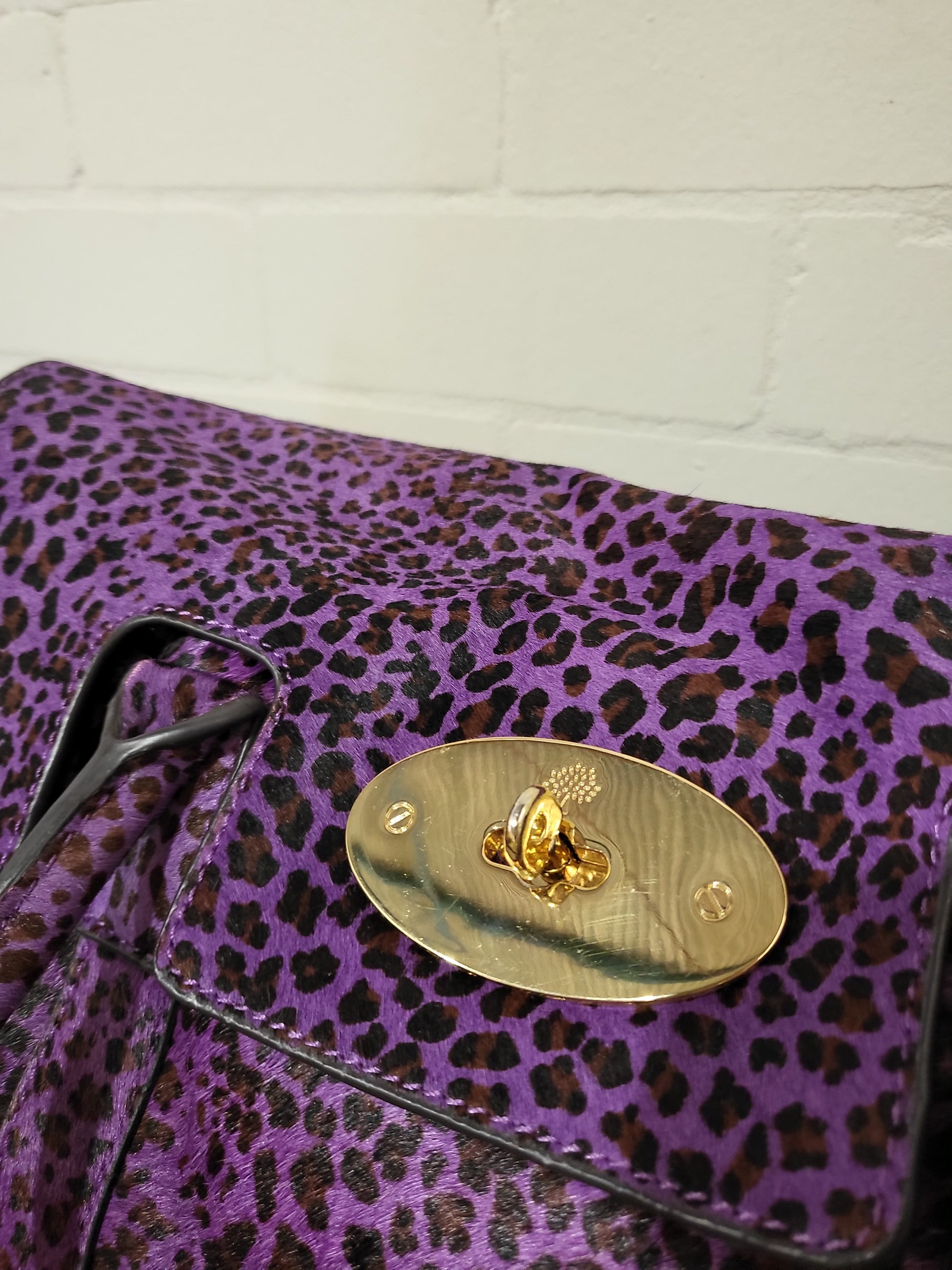Close-up of Mulberry Bayswater lock and purple leather trim against leopard pony hair.