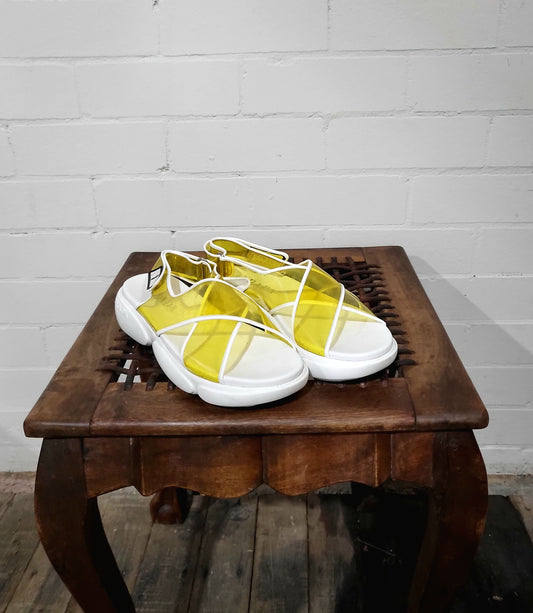 Front view of Prada transparent yellow sandals with white trim and velcro closure, size 9.