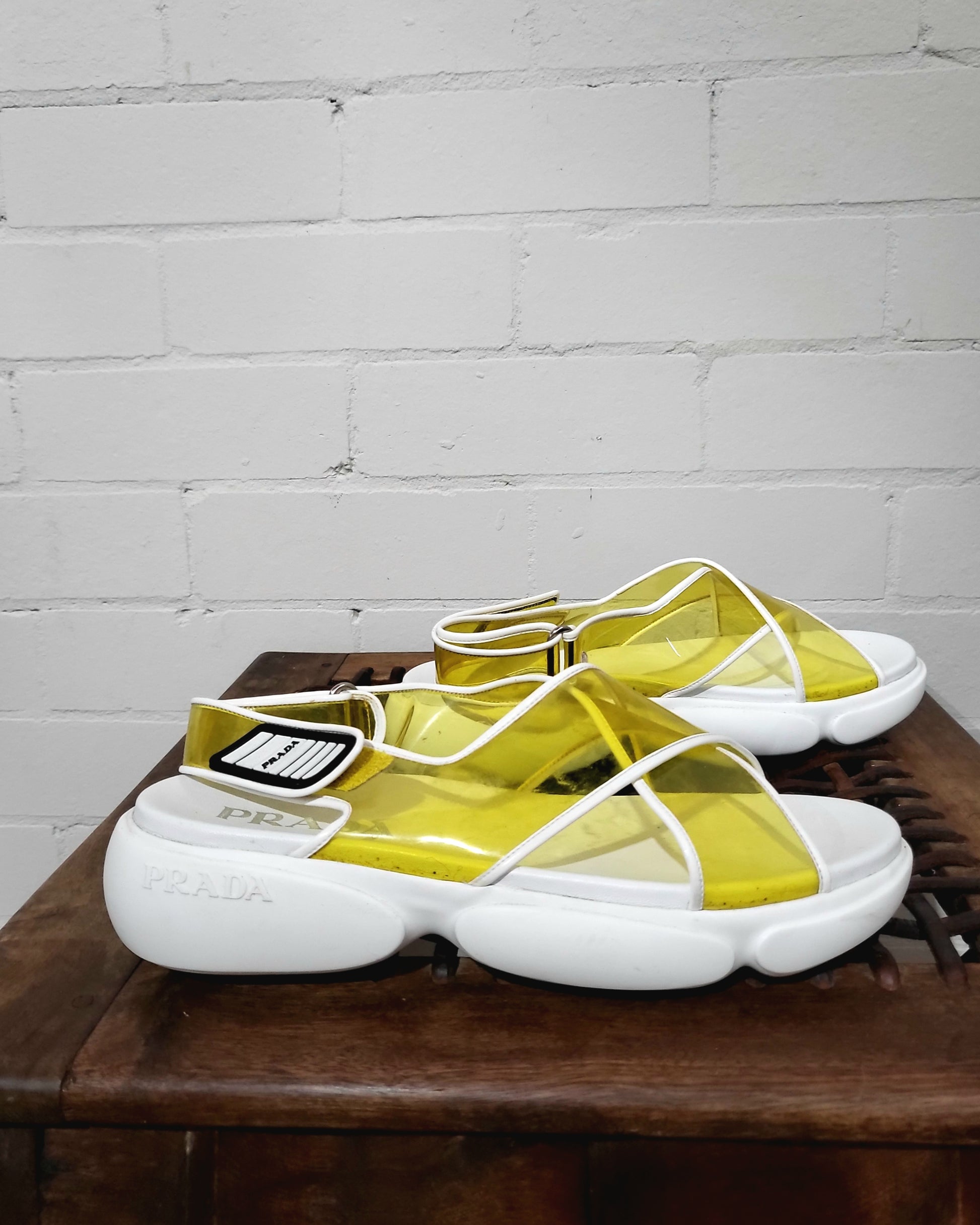 Side profile of Prada yellow criss-cross strap sandals with chunky white sole.