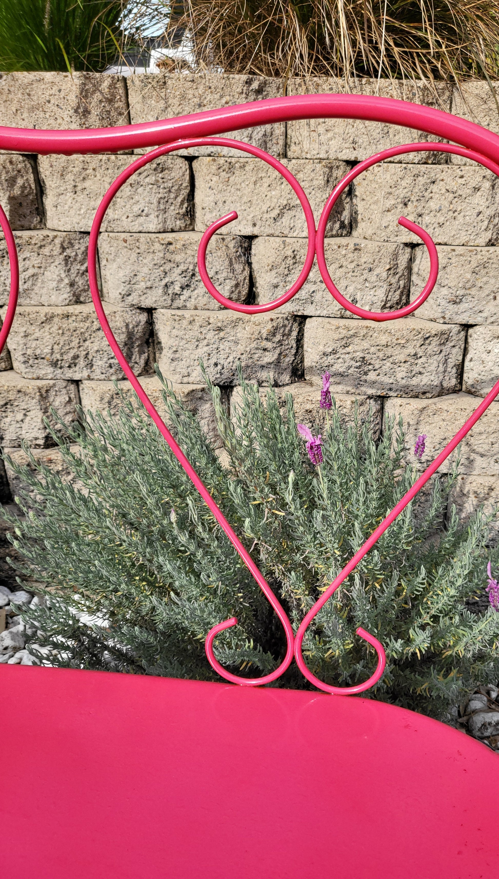 Close-up of French wrought iron love seat showing curved heart-shaped backrest and scrolled arms.